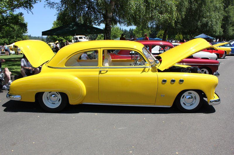 A yellow car with the hood up is parked in a parking lot