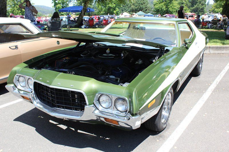 A green car with the hood open is parked in a parking lot