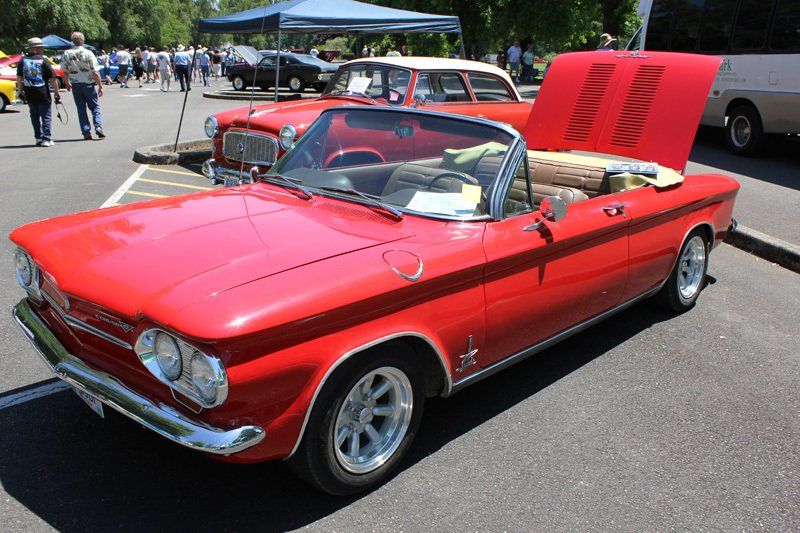 A red car with the hood up is parked in a parking lot