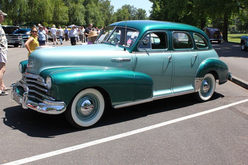 A green car with white tires is parked in a parking lot