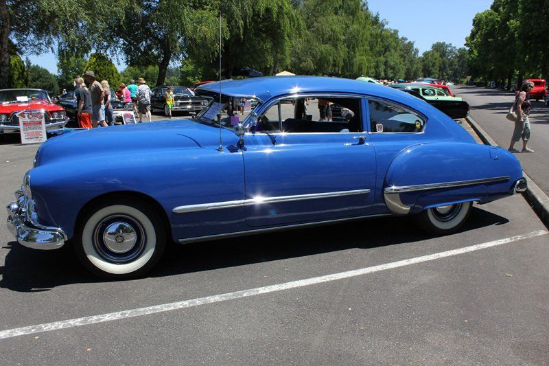 A blue car with white tires is parked in a parking lot