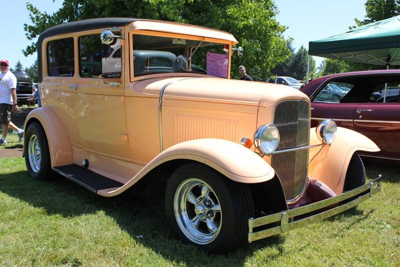 An old car is parked in the grass at a car show.