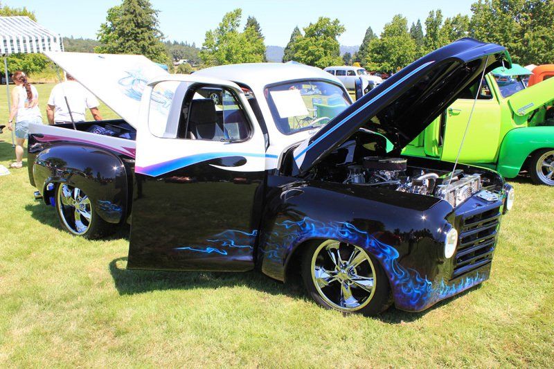 A black and white truck with the hood up is parked in the grass