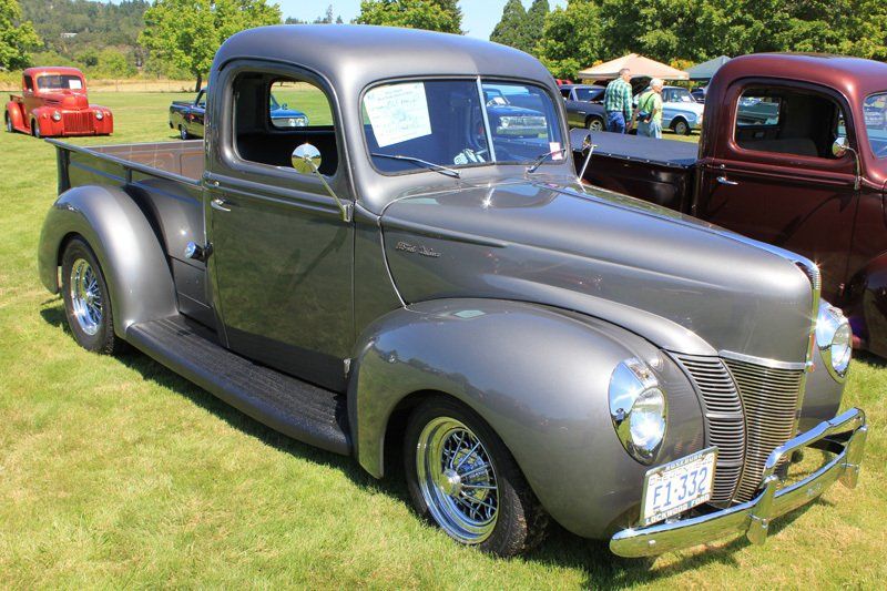 A gray pickup truck is parked in a grassy field.