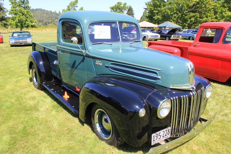 A blue and black pickup truck is parked in a grassy field.