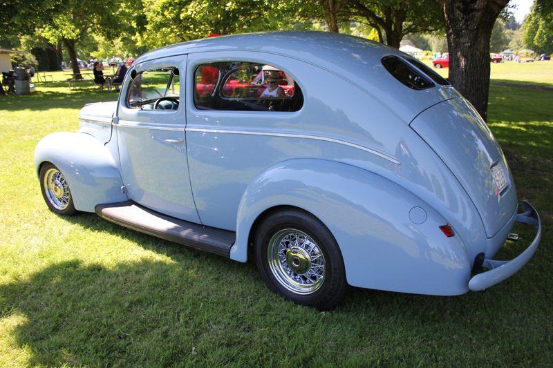 A light blue car is parked in a grassy field.