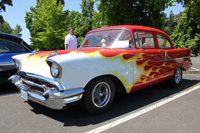 A red and white car with flames painted on the side is parked in a parking lot.