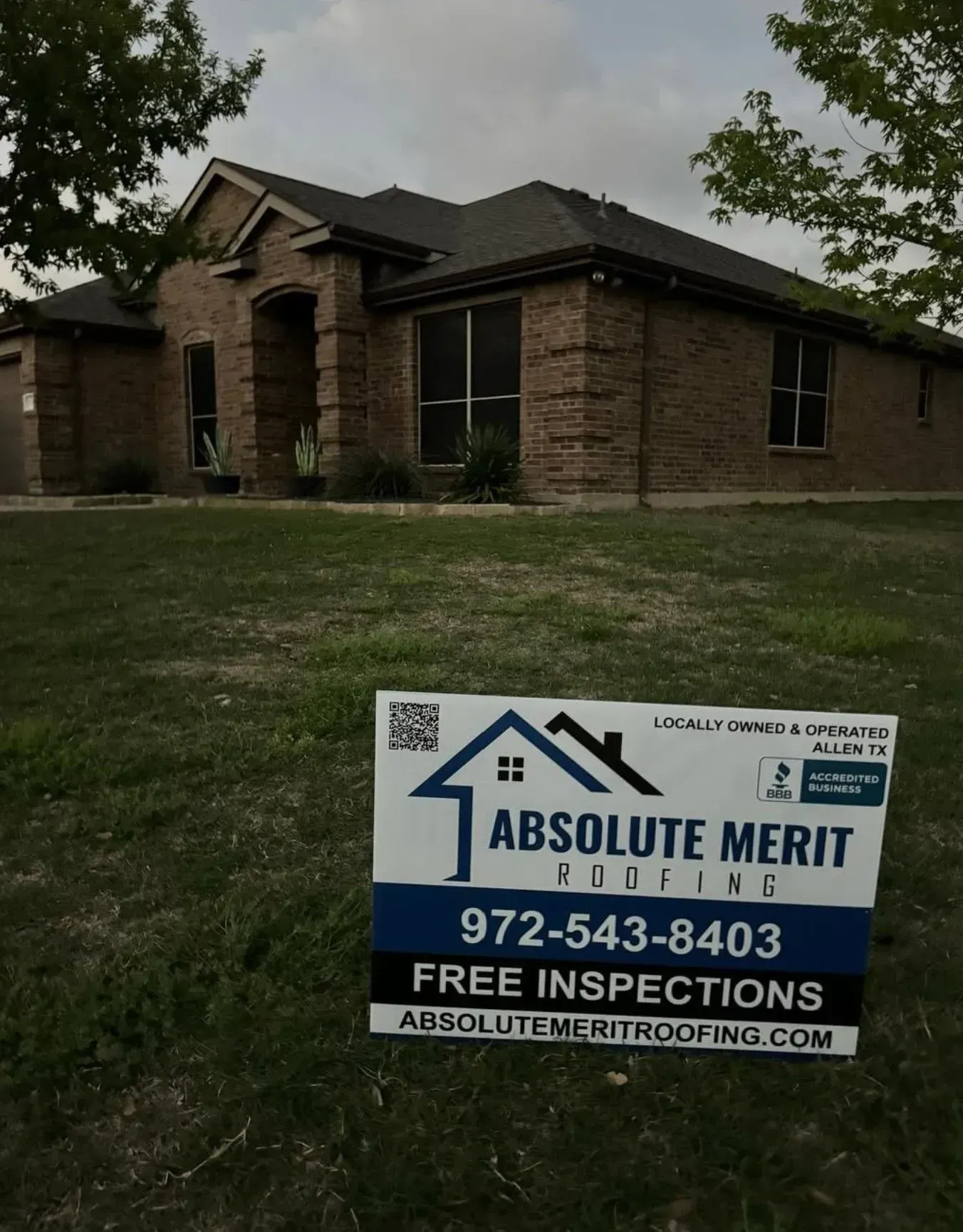 A sign for absolute merit roofing is in front of a house