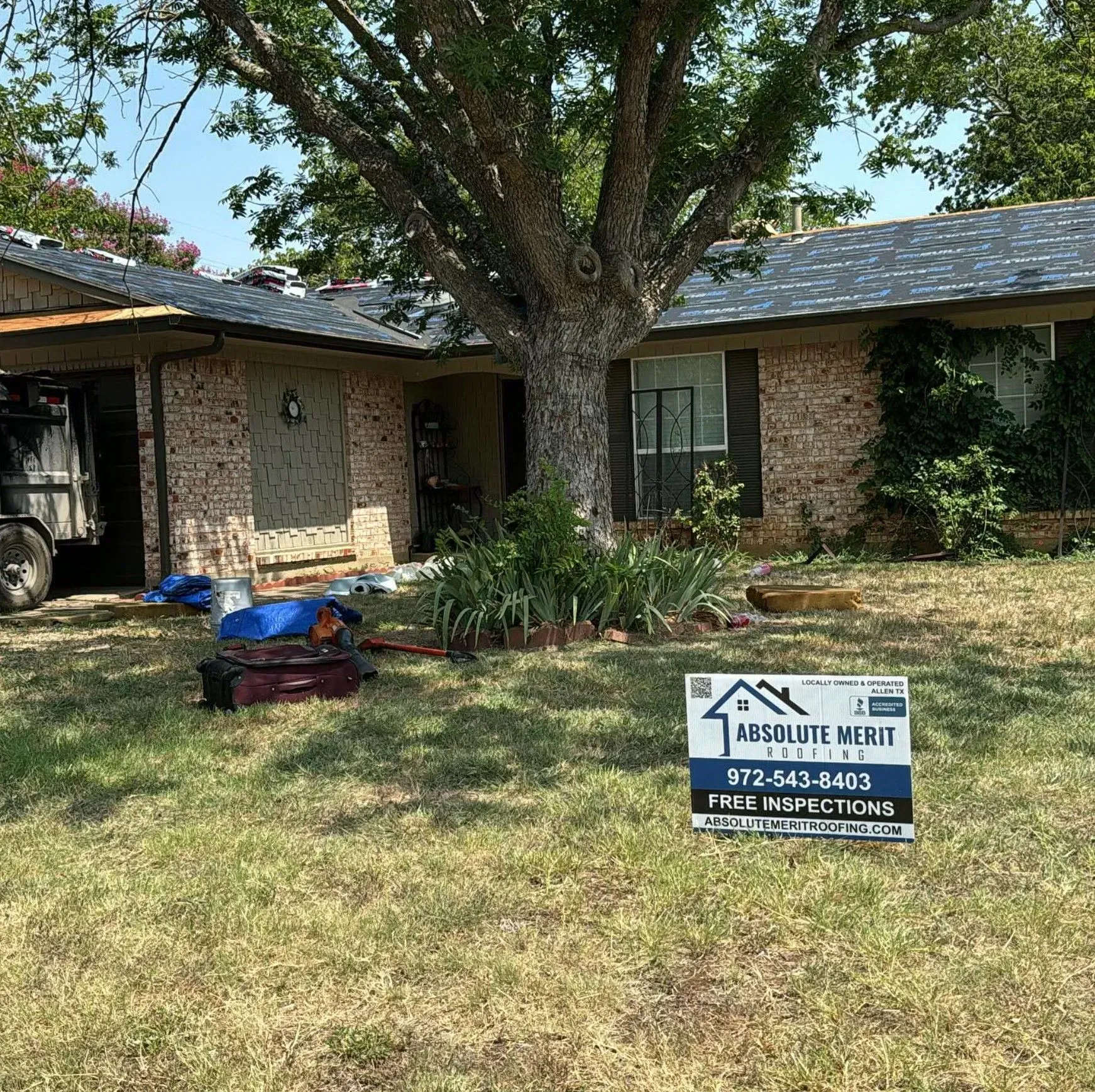 A house with a roof that is being installed and a sign in front of it.