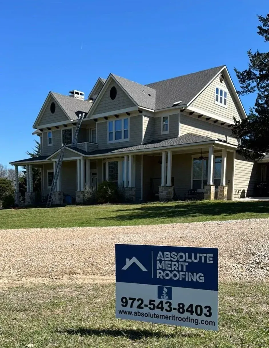 A house with a sign in front of it that says absolute merit roofing