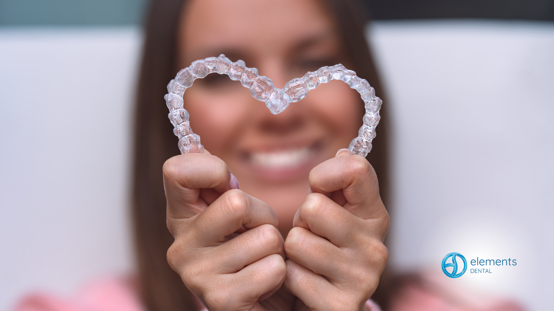 A woman is holding a heart shaped retainer in her hands.