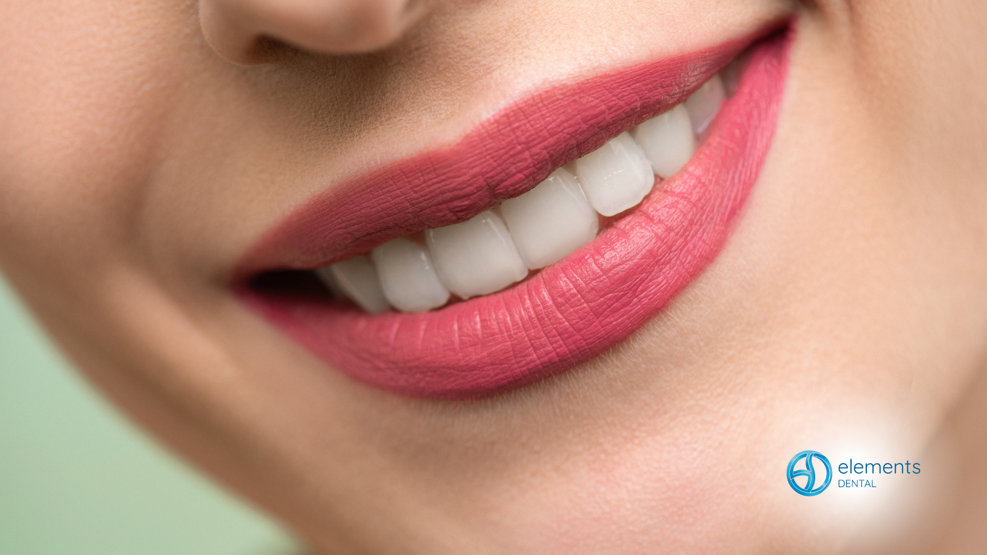 Close-up of a smiling person with bright white teeth and vibrant red lipstick.