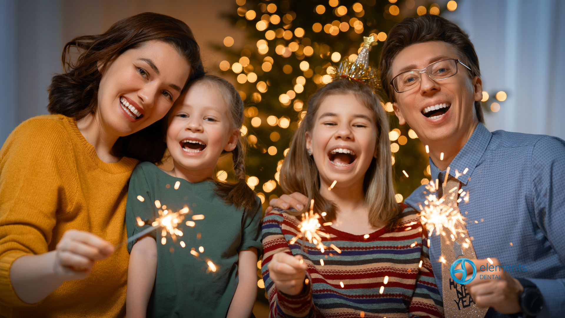 A family is holding sparklers in front of a christmas tree.