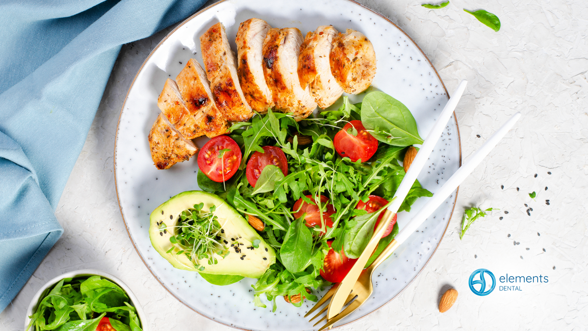 A plate of food with chicken , avocado , tomatoes and lettuce on a table.