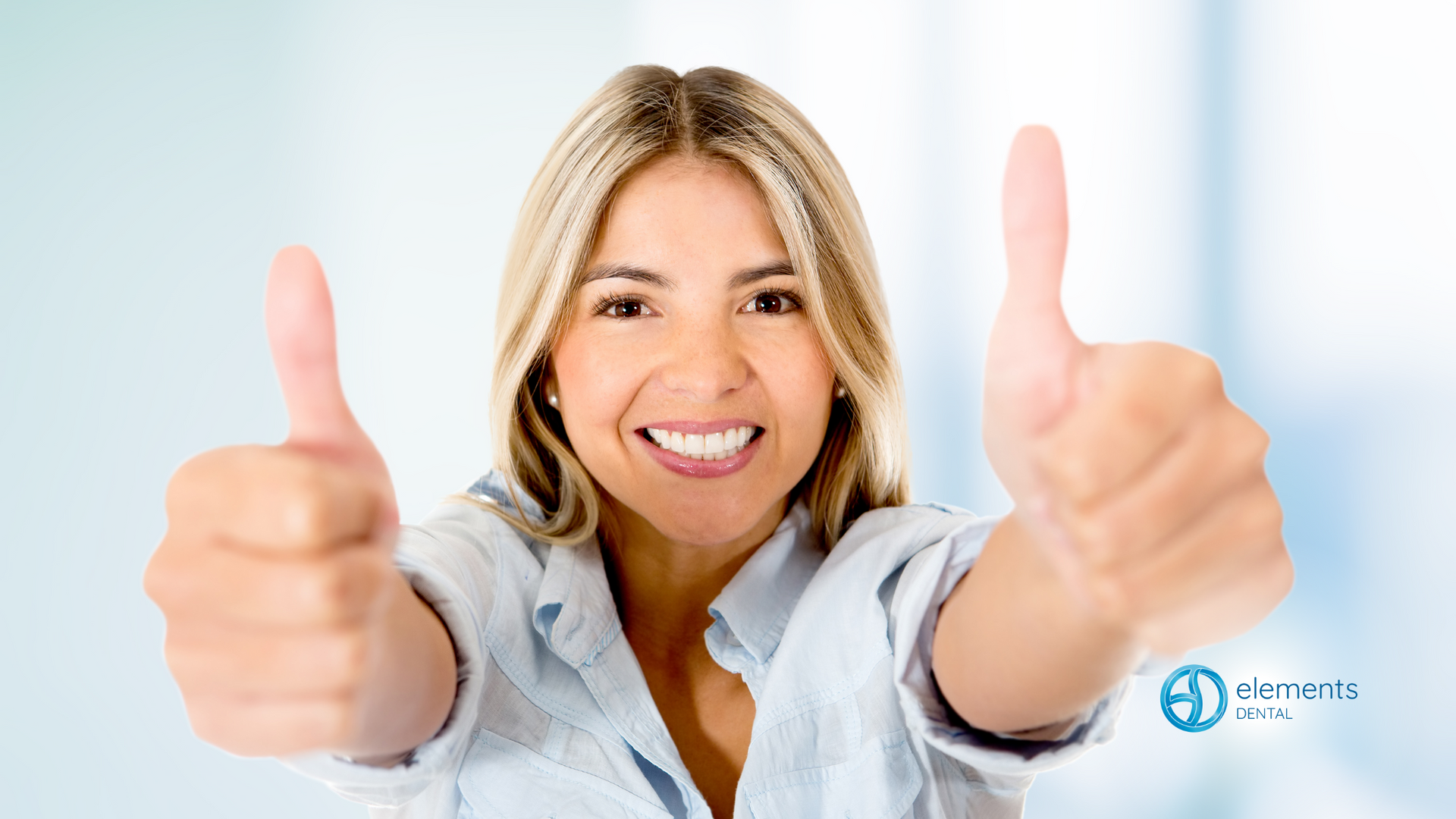 A woman is smiling and giving two thumbs up.