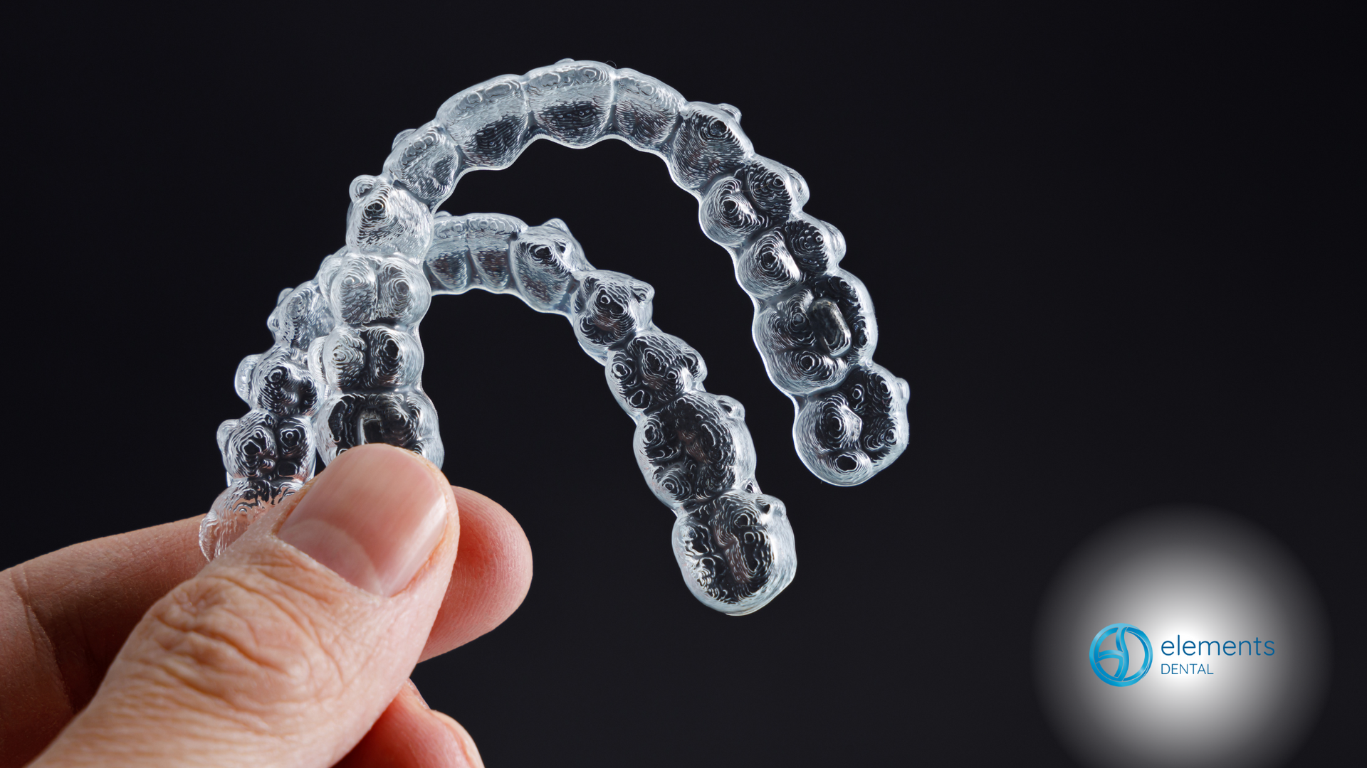 A person is holding a pair of clear braces in their hand.