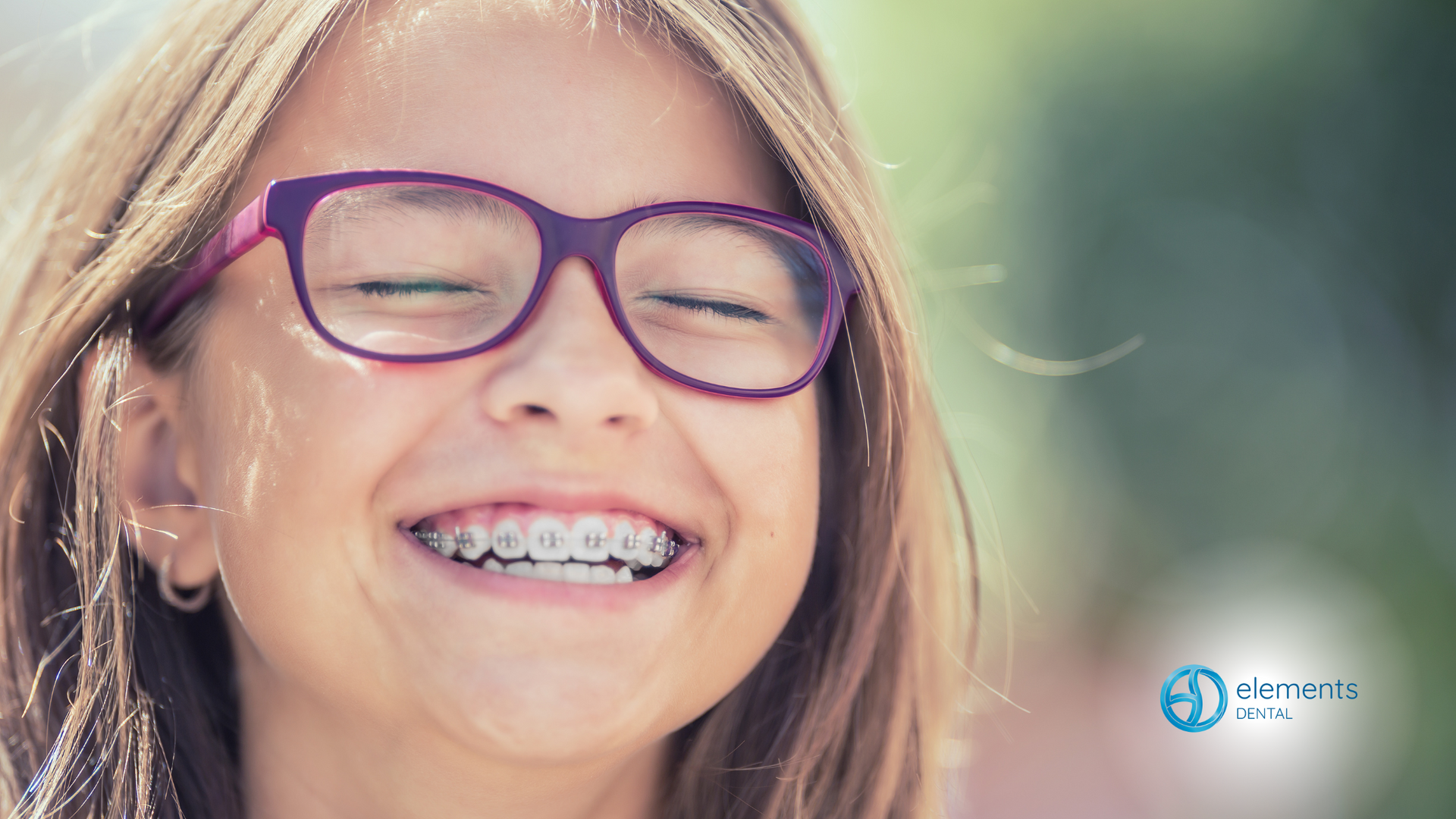 A young girl wearing glasses and braces is smiling.