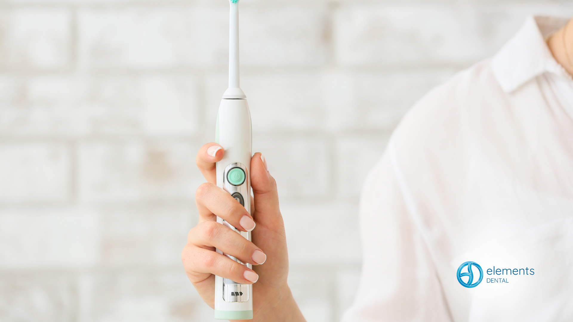 A woman is holding an electric toothbrush in her hand.