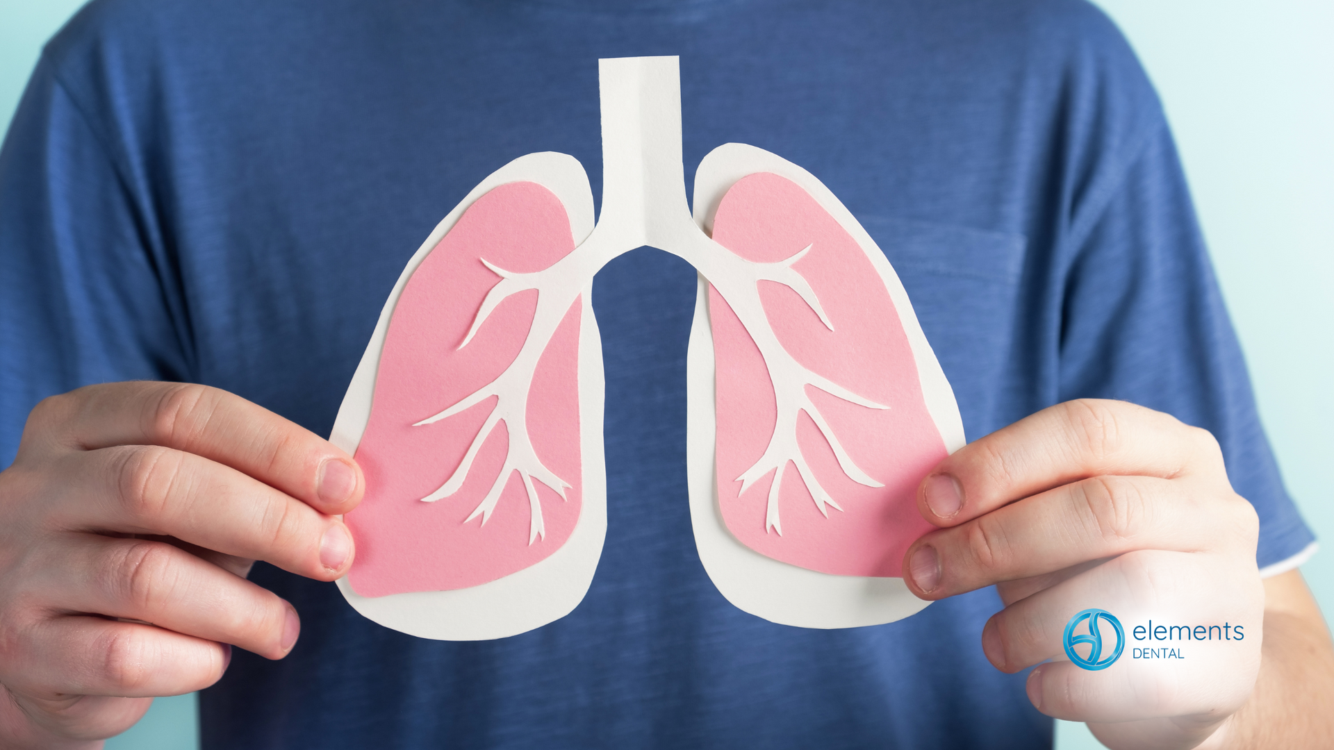 A man is holding a paper cut out of his lungs.