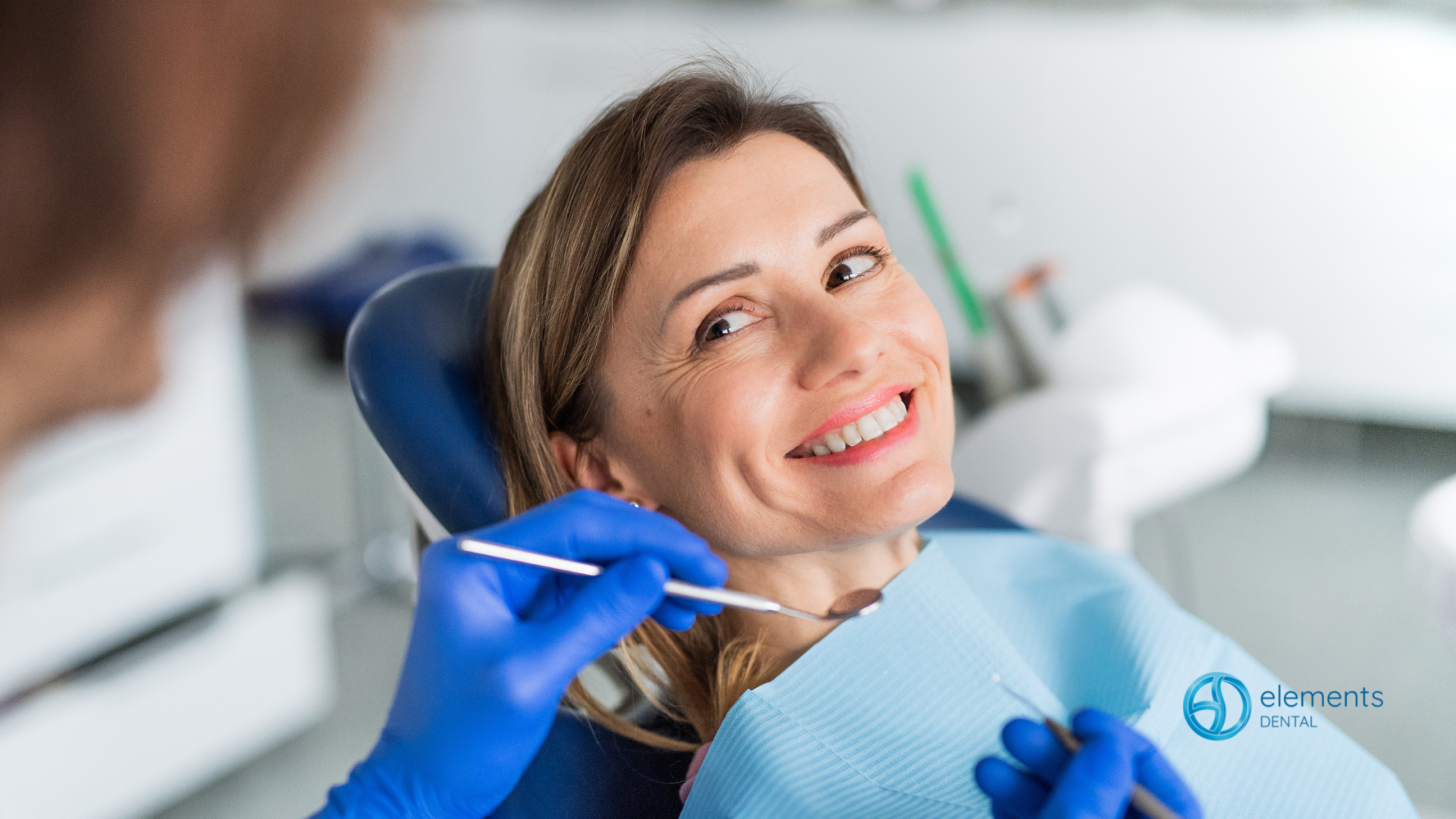 A woman is smiling while having her teeth examined by a dentist.