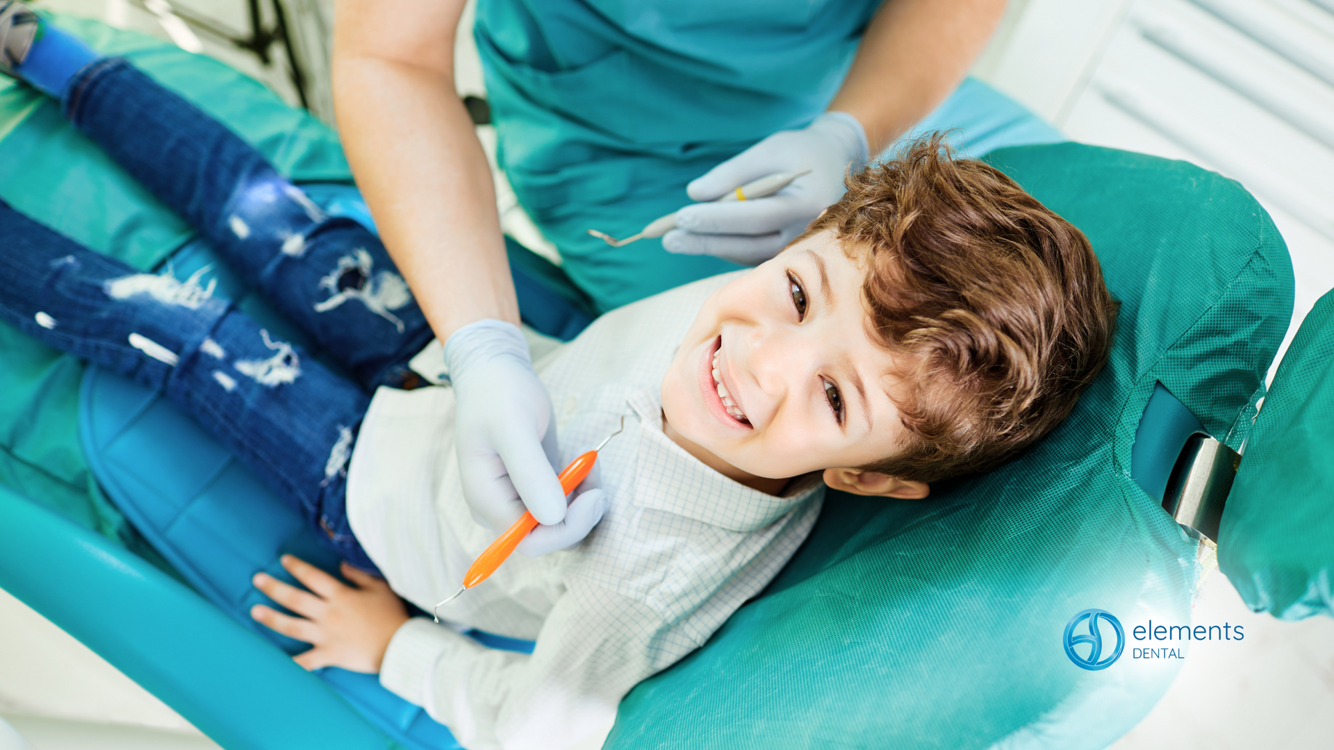 A young boy is laying in a dental chair while a dentist examines his teeth.