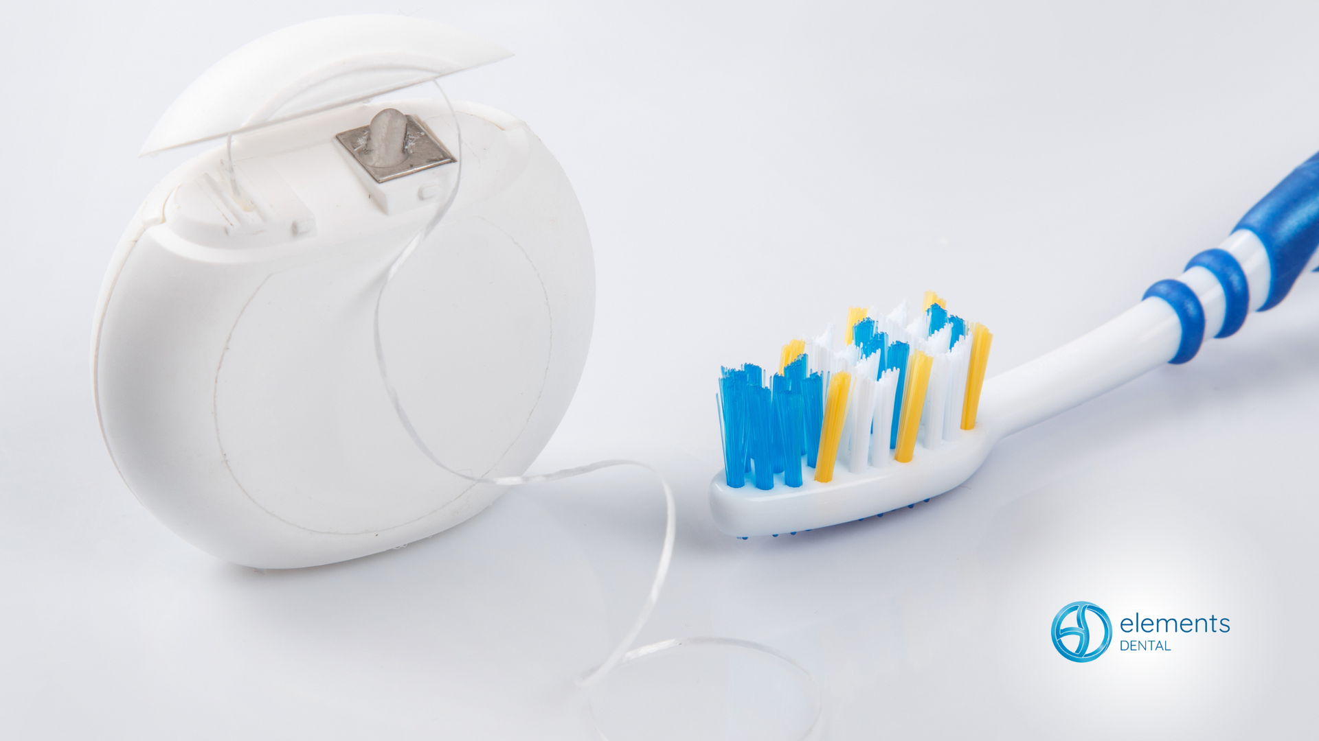 A toothbrush and floss are on a white surface.