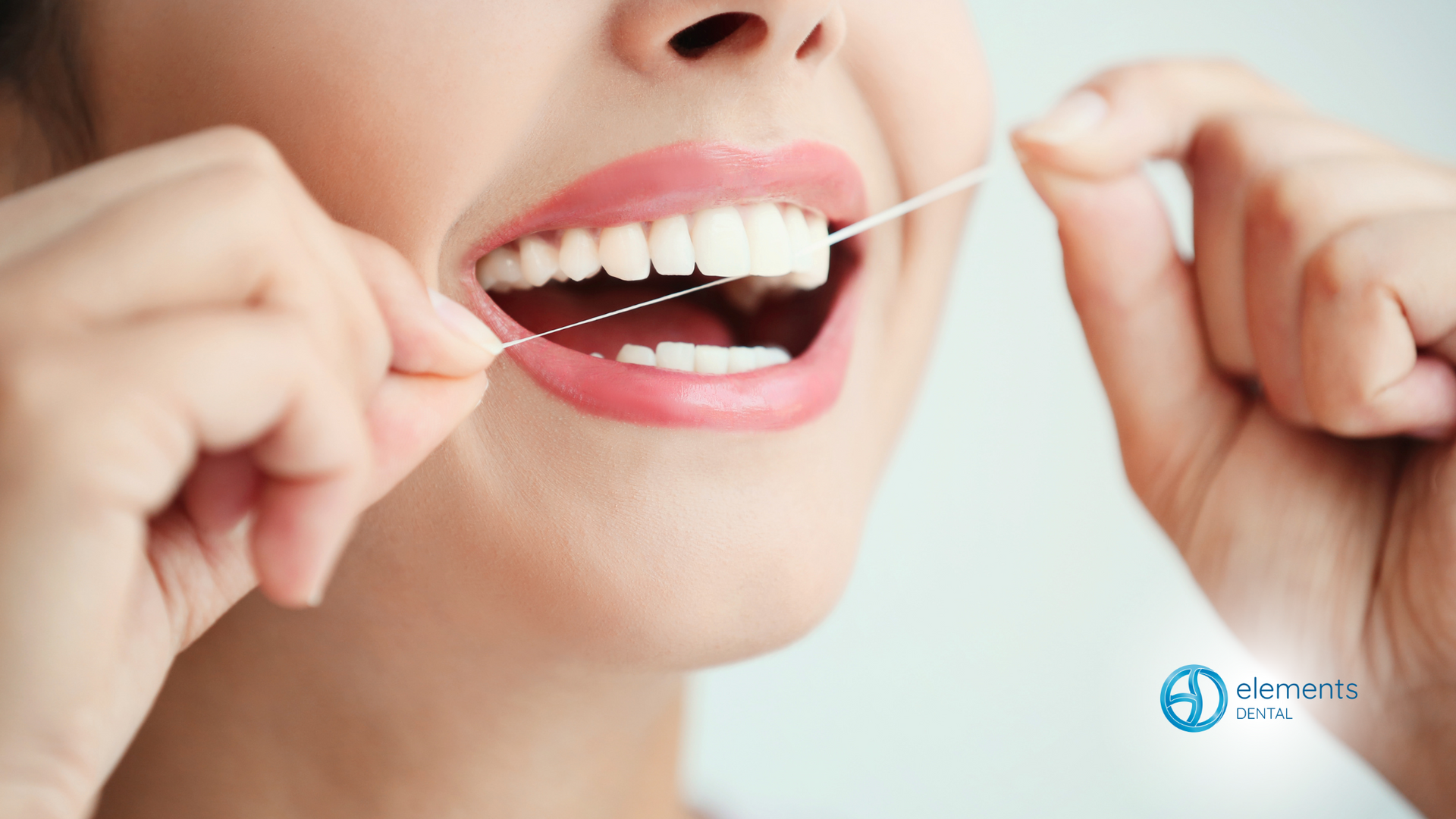 A woman is flossing her teeth with a dental floss.