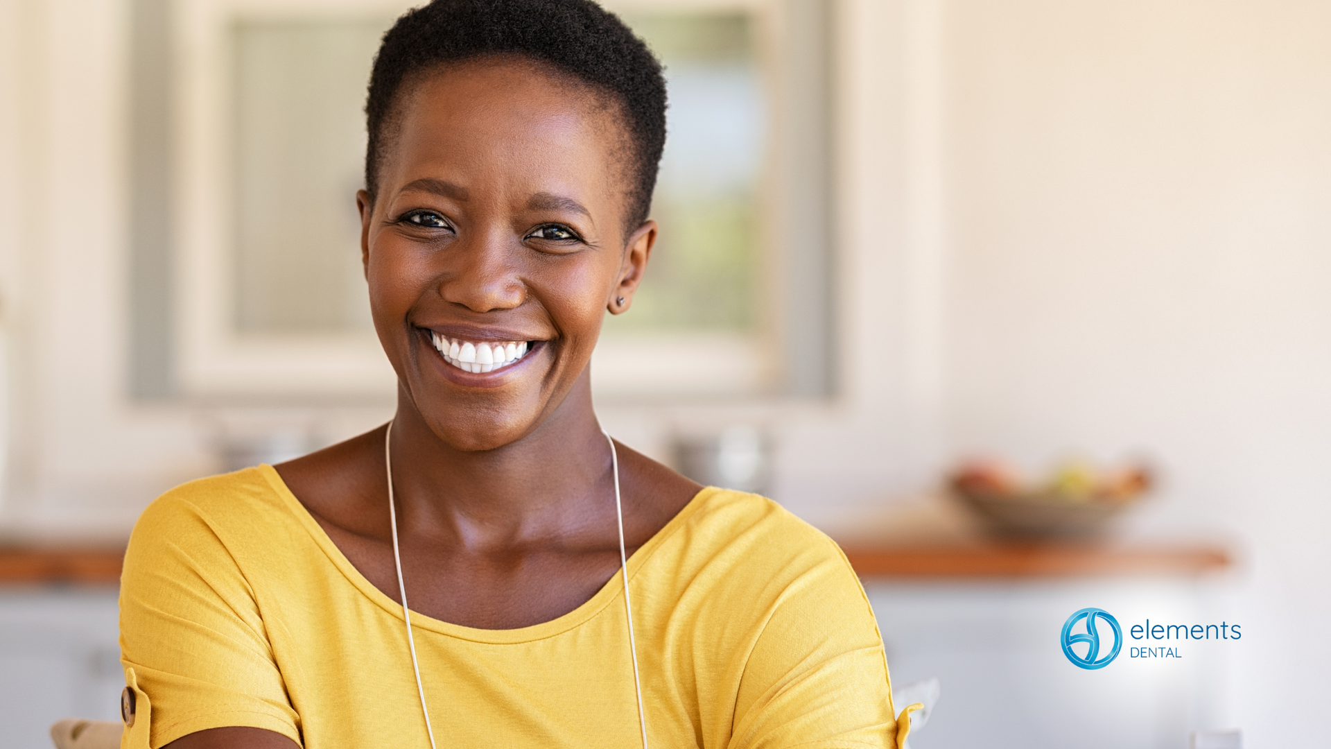 A woman in a yellow shirt is smiling for the camera.