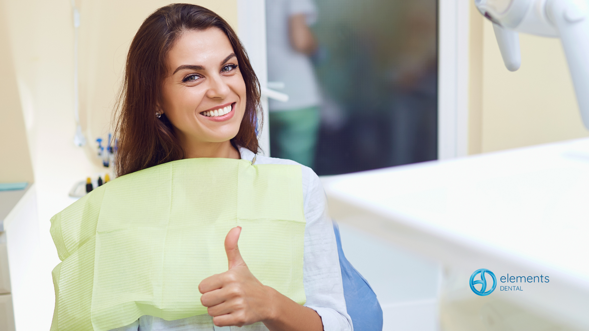 A woman is giving a thumbs up while sitting in a dental chair.