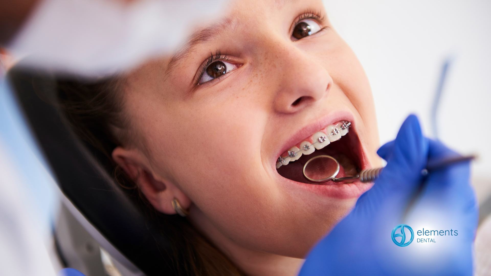 A young girl is getting her teeth examined by a dentist.