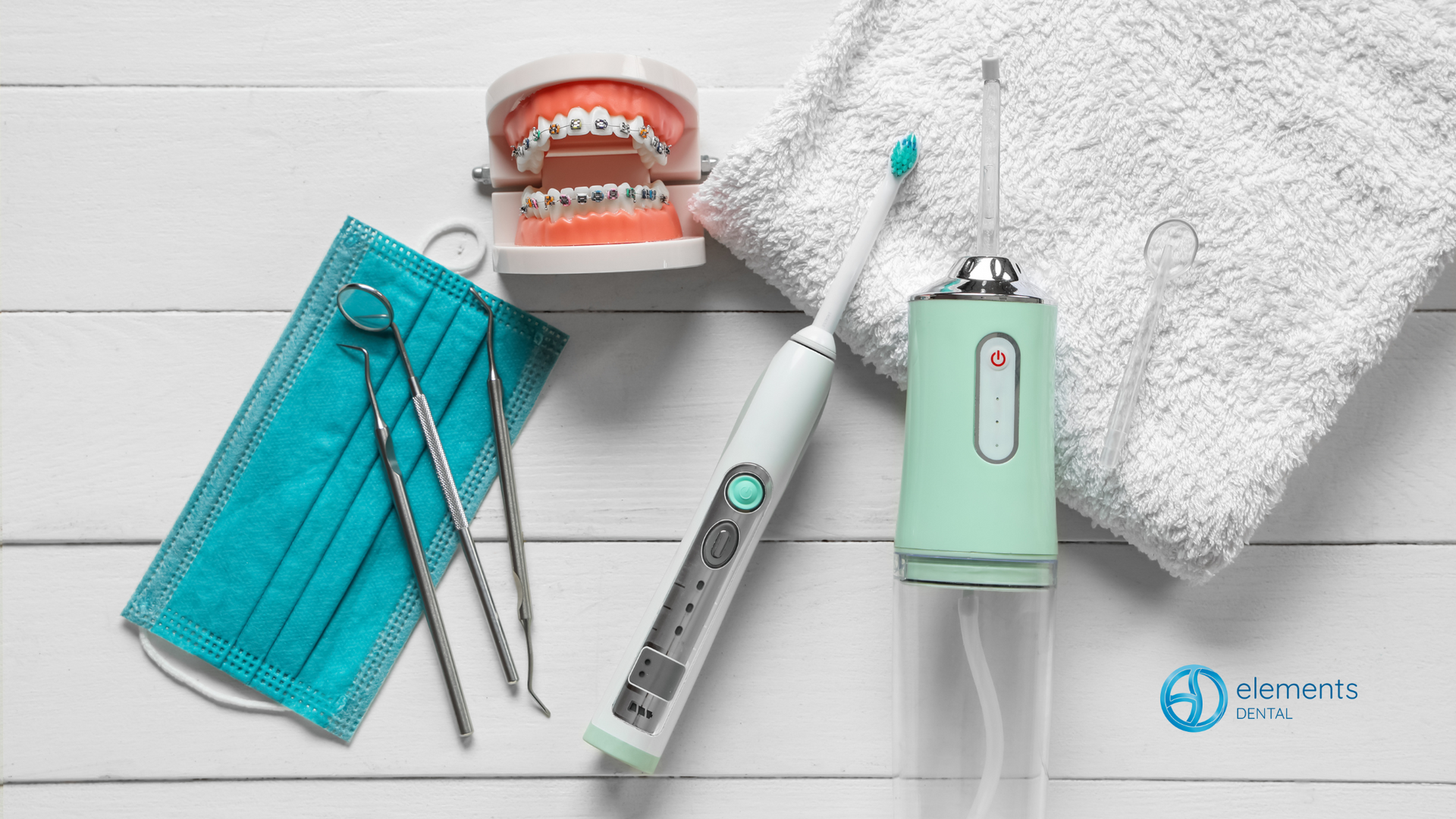 A toothbrush , dental instruments , a mask and a model of teeth are on a table.