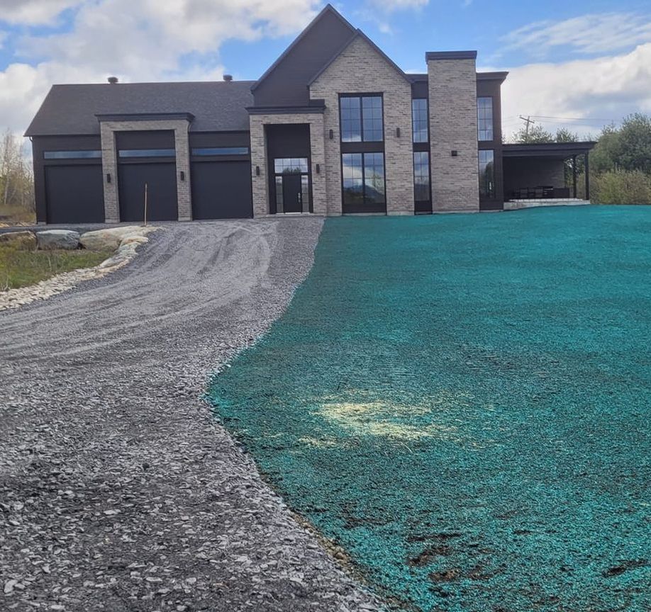 Maison moderne avec allée en gravier et pelouse traitée aux végétaux.