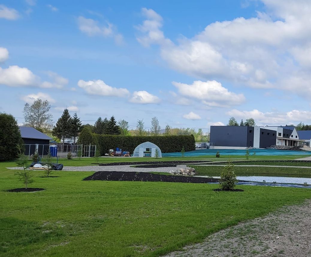 Un homme et un enfant conduisent un tracteur tondeuse vert dans une cour herbeuse.