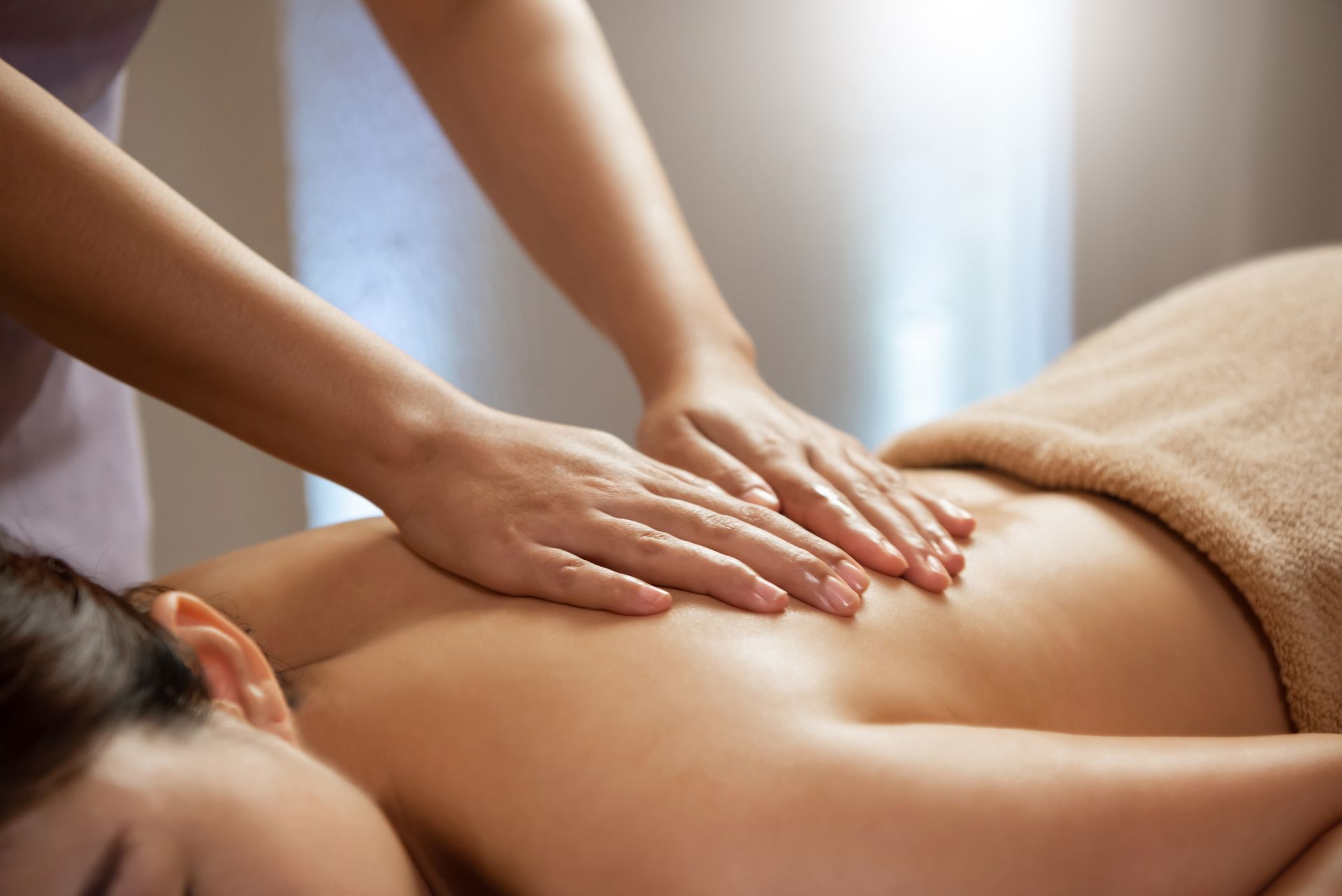 Person receiving a back massage at a spa, hands massaging back.