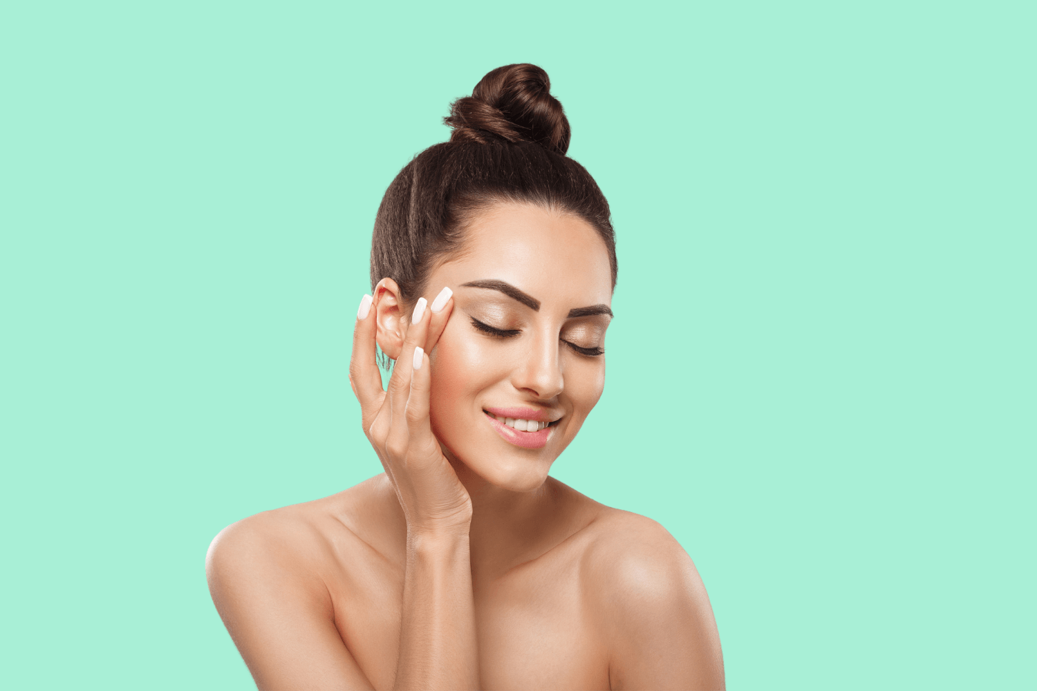 A woman is touching her face with her hand and smiling.