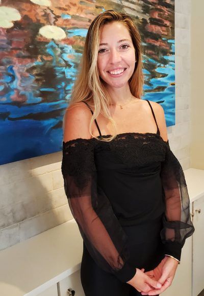 A woman in a black dress is standing in front of a painting.