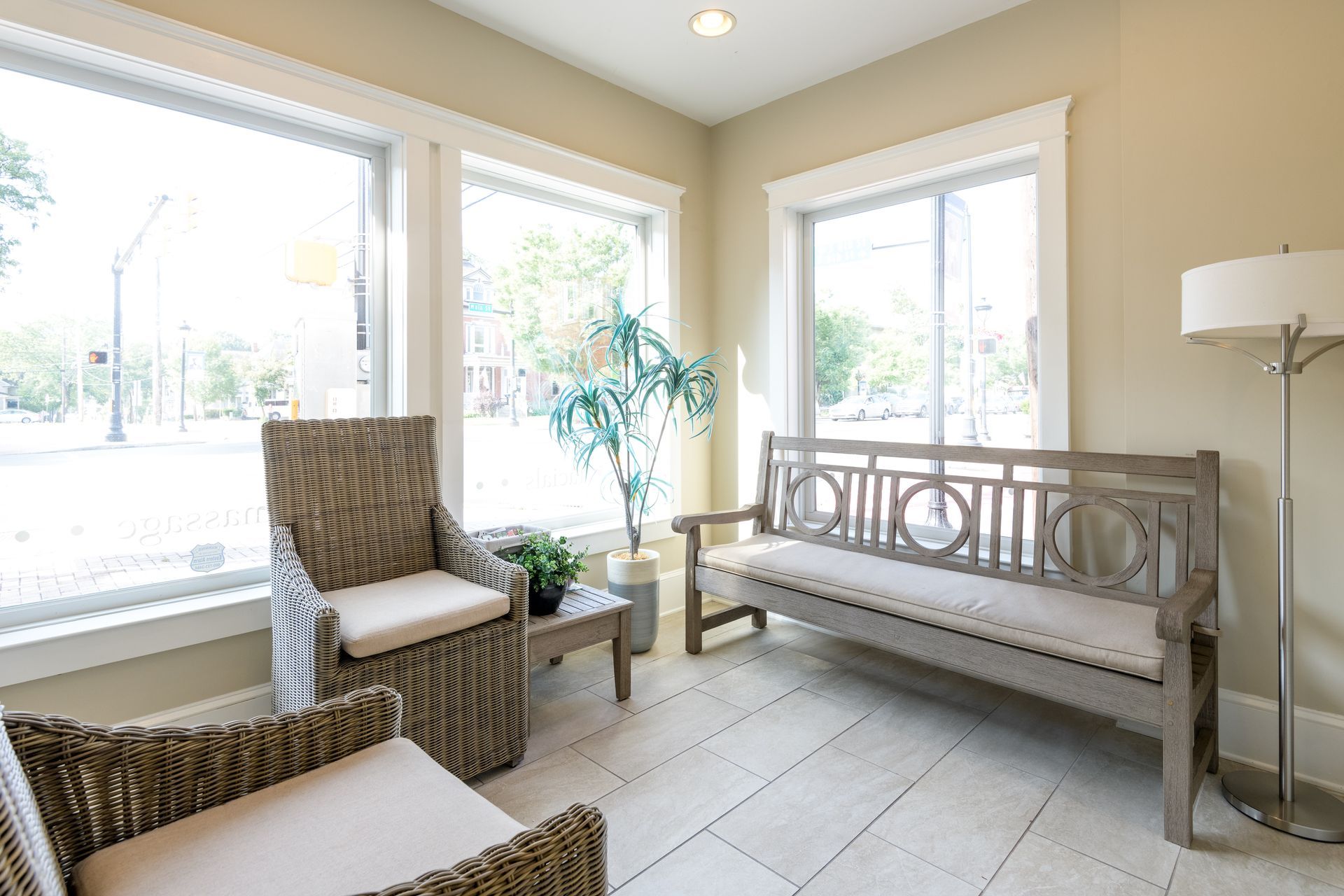 A waiting room with a couch , chairs , and a lamp.