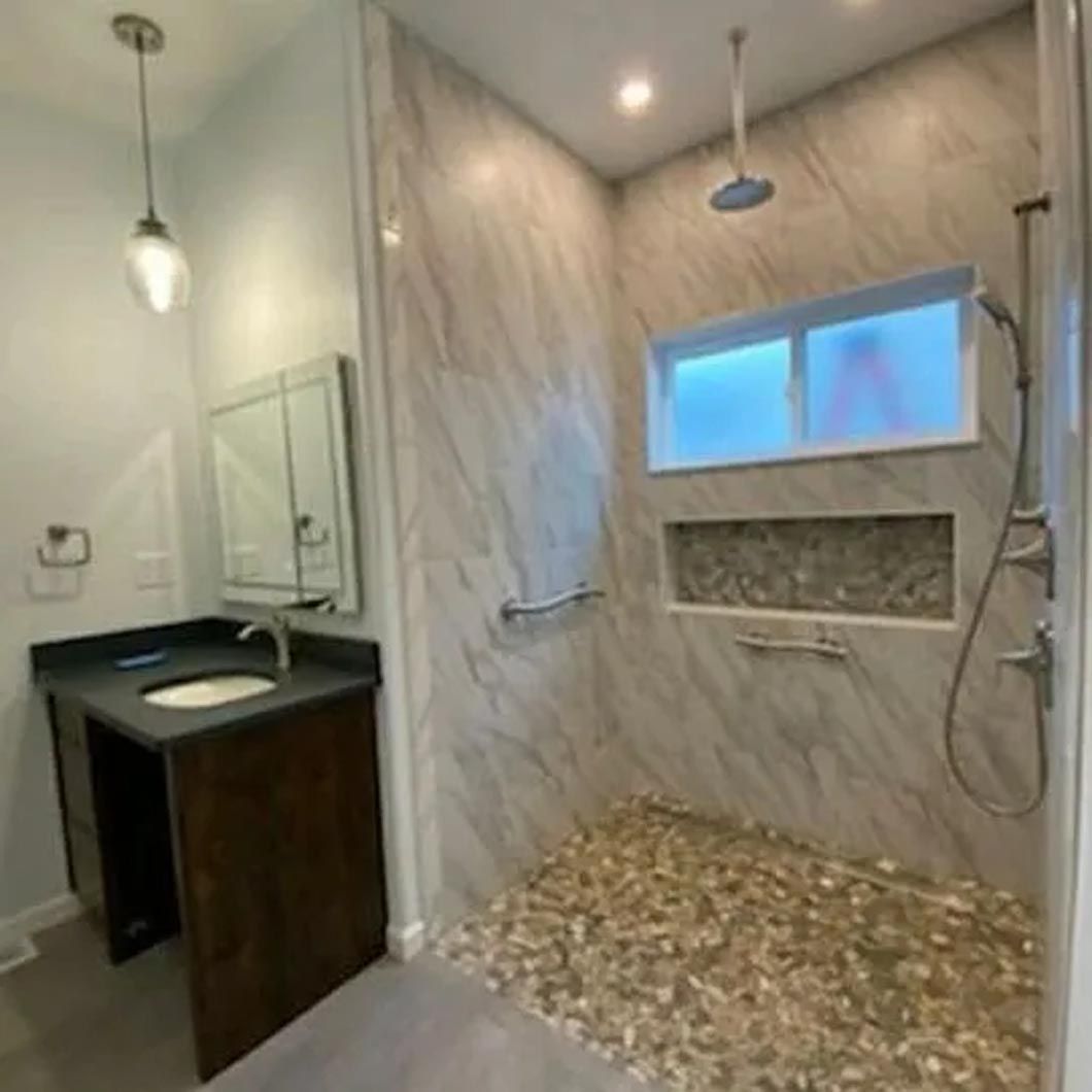 A bathroom with a walk in shower , sink and mirror.