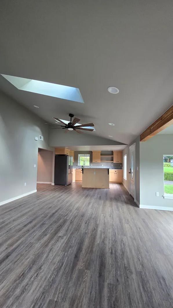 A large empty room with hardwood floors and a skylight in the ceiling.