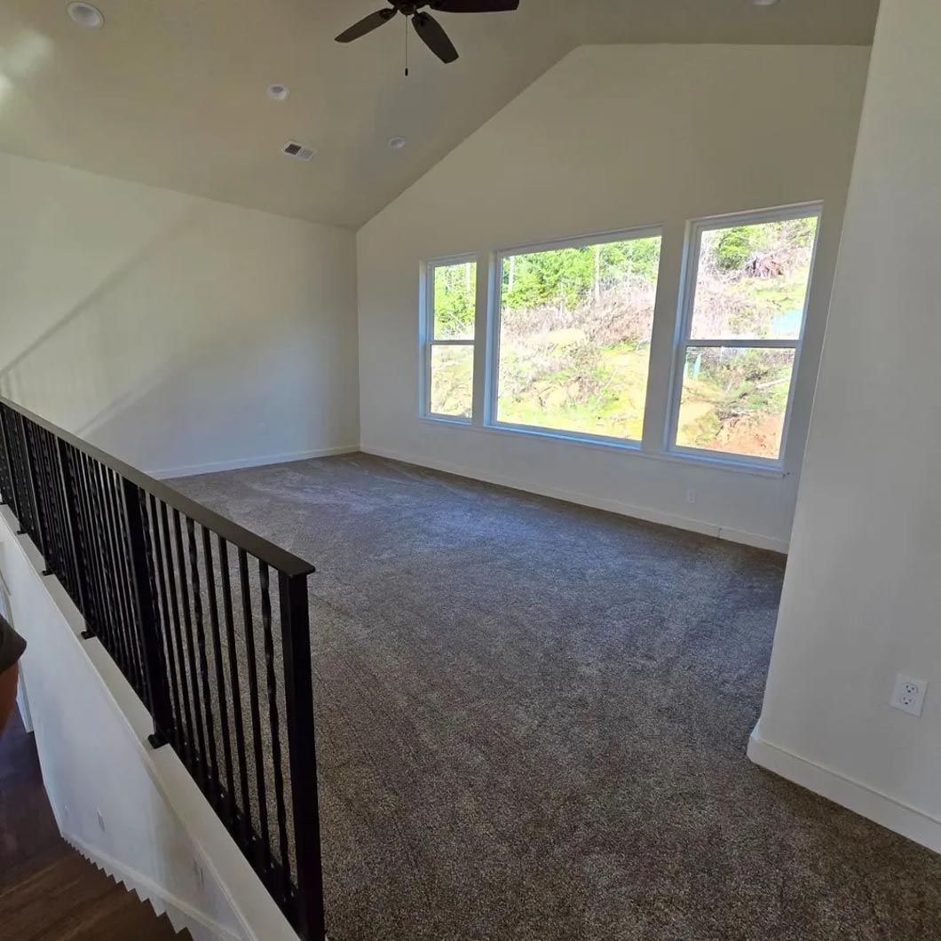 An empty room with a ceiling fan and stairs leading up to it.