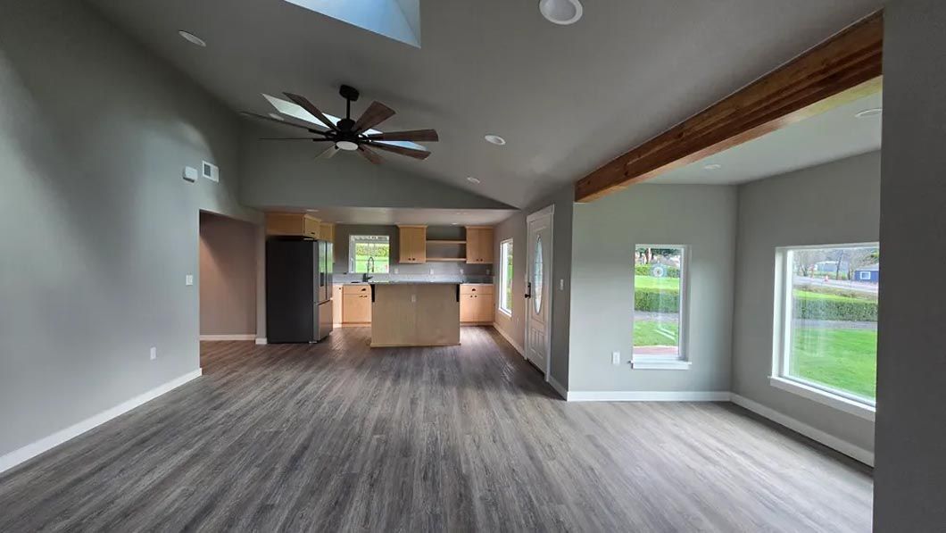 An empty living room with hardwood floors and a ceiling fan.