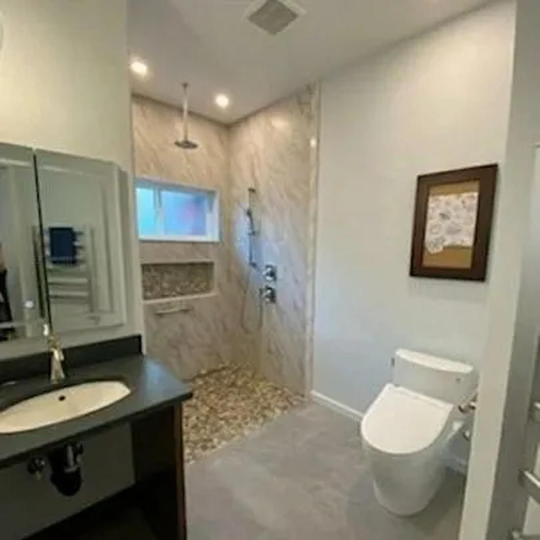 A bathroom with a toilet , sink and shower.
