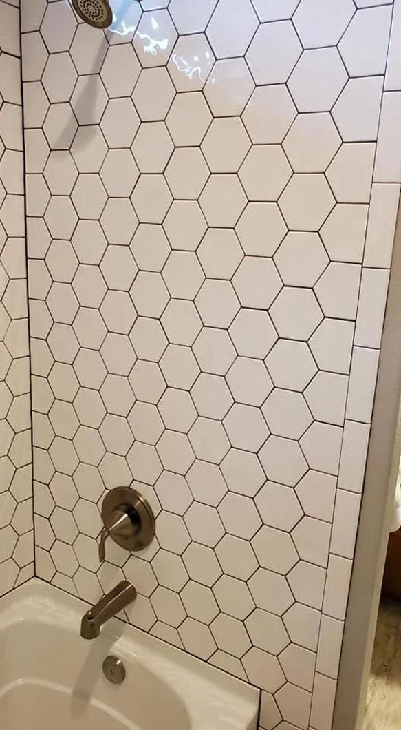 A bathroom with a bathtub , shower , toilet and honeycomb tiles.