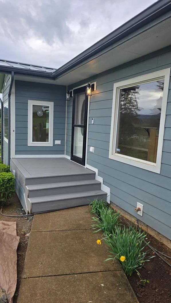 A blue house with stairs leading up to the front door and a porch.