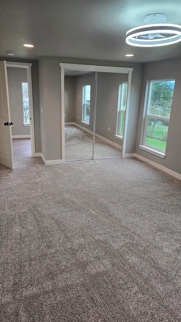 A large empty room with a lot of windows and carpet.