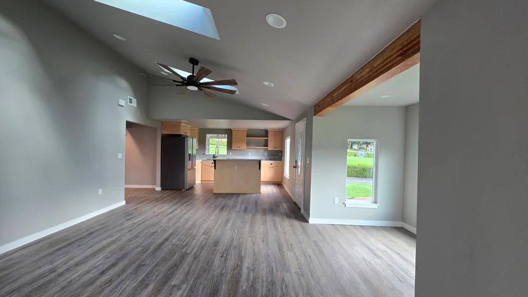 An empty living room with hardwood floors and a ceiling fan.