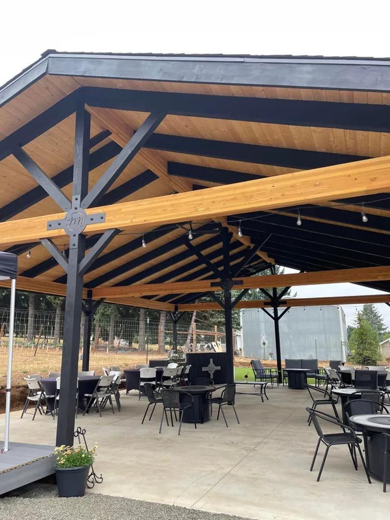 A large covered area with tables and chairs under a wooden roof.