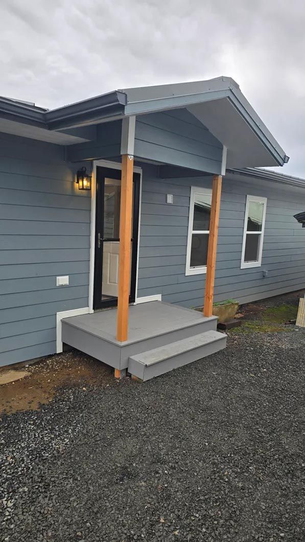 A blue house with a porch and stairs in front of it.