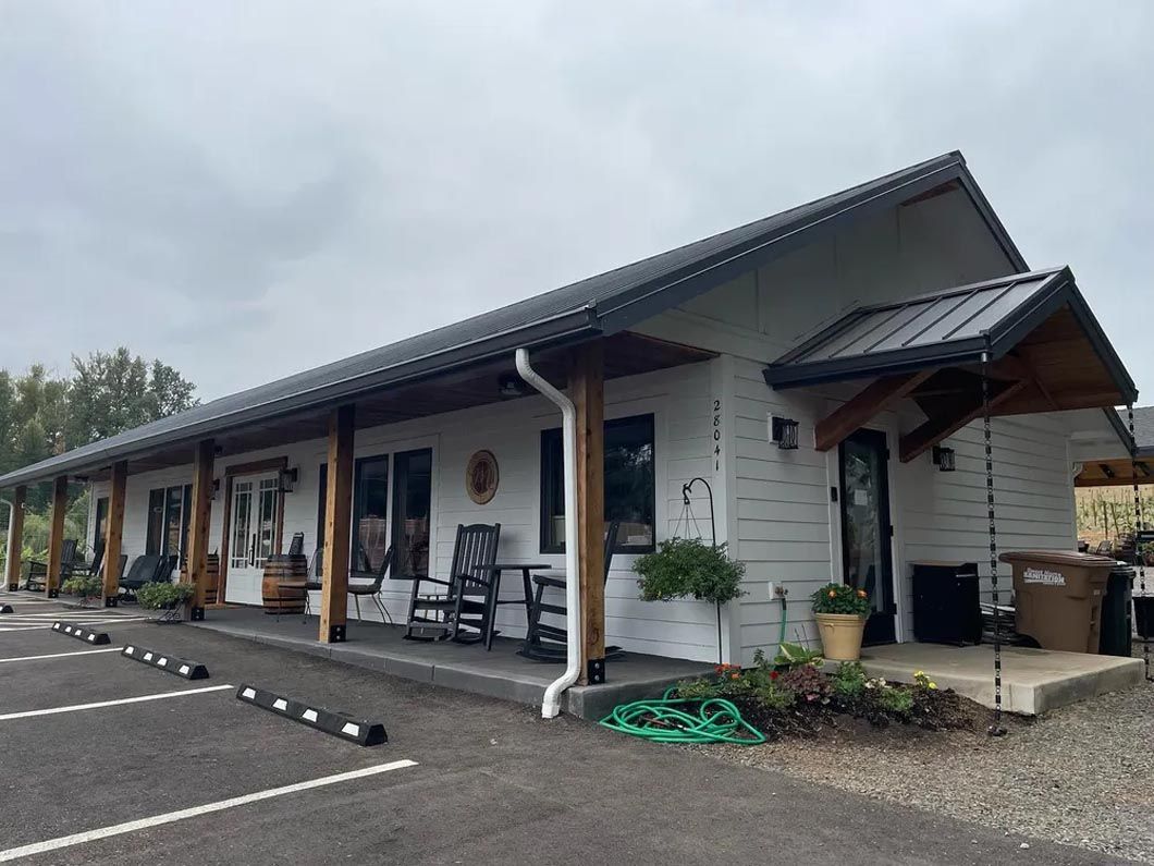 A large white building with a porch and rocking chairs in front of it.