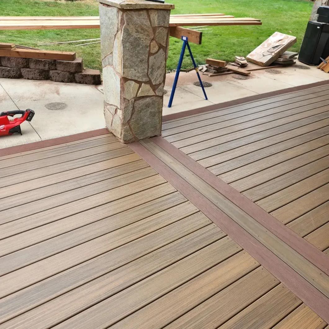 A wooden deck with a stone pillar in the background is being built.